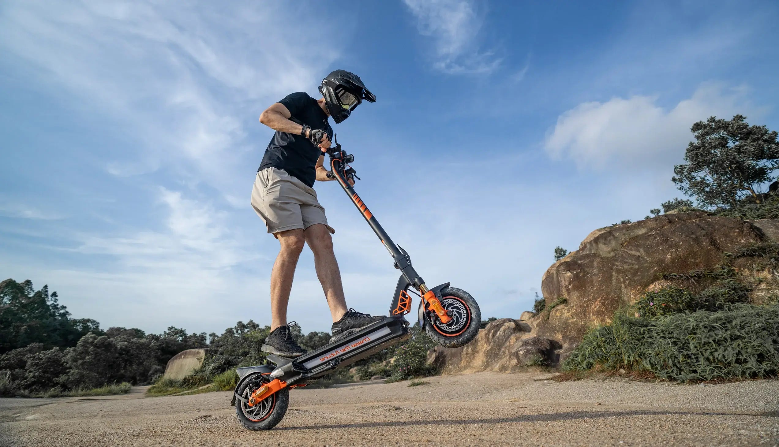 Male rider performing wheelie on CUNFON RZ1000 electric scooter in sandy hill terrain, showcasing 2400W dual motor power, 38° climbing capability, and front and rear dual shock absorbers for all-terrain control.